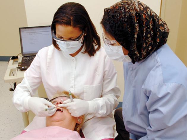 two dental hygienists working with patient in dental chair