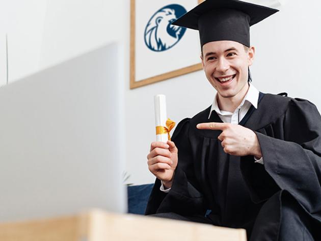 Male student holding a diploma for graduation on a blue couch